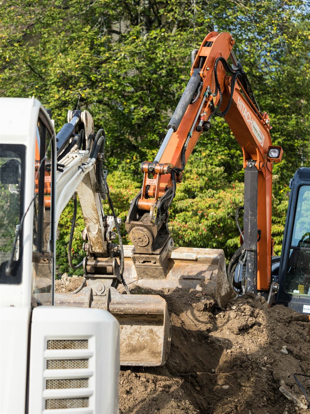 Compact excavators digging soil for a residential excavation project