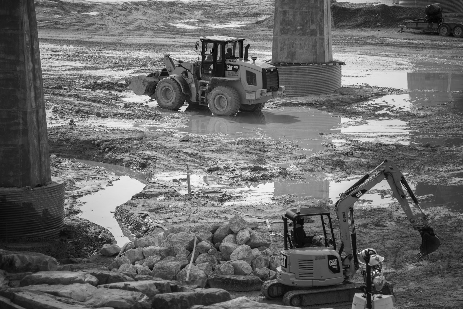 Loader and excavator on a wet, graded construction site during earthwork